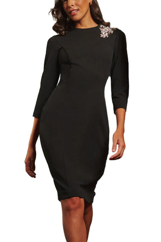 Woman wearing a black dress with floral embellishments in an urban setting.